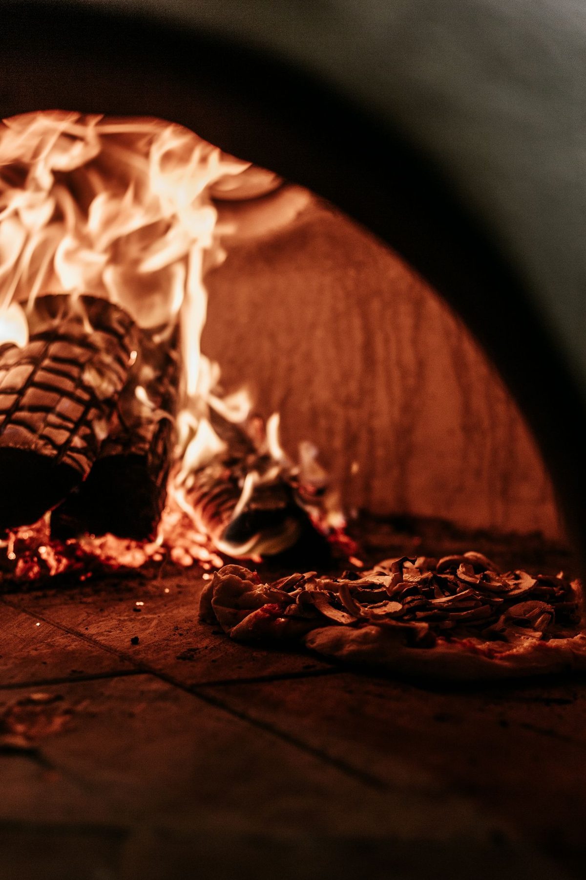 Pizza assando em forno a lenha com fogo e fumaça
