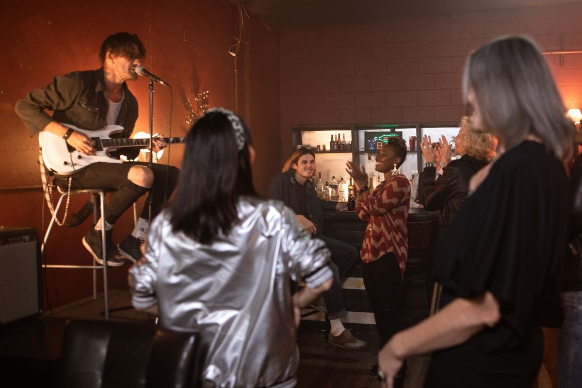 Músico tocando guitarra em bar com público